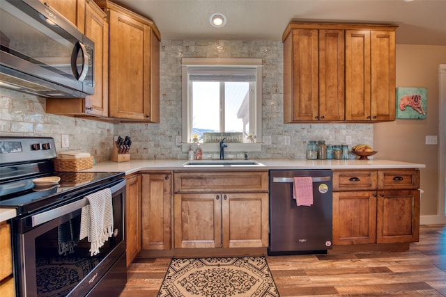 kitchen featuring brown cabinetry, stainless steel appliances, light countertops, light wood-style floors, and a sink