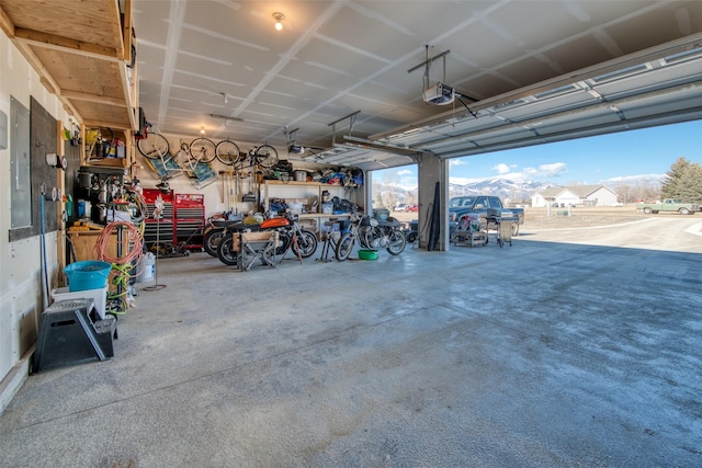 garage with a garage door opener, electric panel, and a workshop area