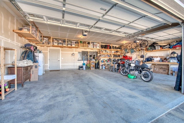 garage featuring a garage door opener, freestanding refrigerator, and a workshop area