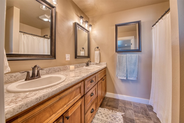 bathroom with a sink, baseboards, and double vanity