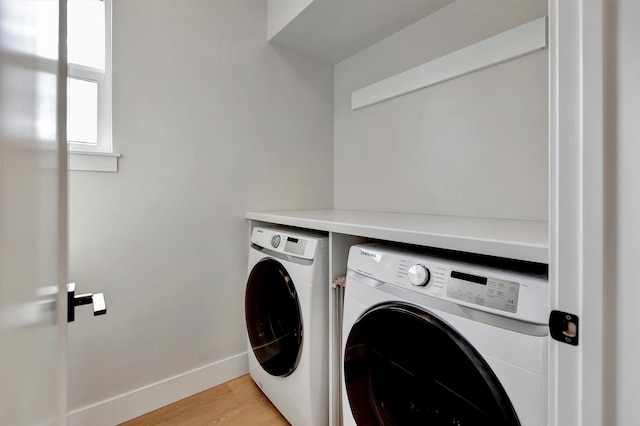 washroom featuring light wood-type flooring, laundry area, baseboards, and separate washer and dryer