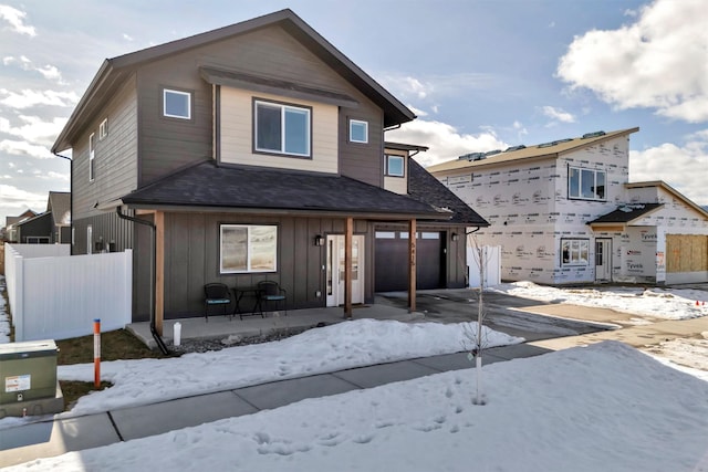 view of front of home featuring board and batten siding, fence, driveway, and a patio