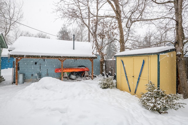 snowy yard featuring a storage unit and an outdoor structure