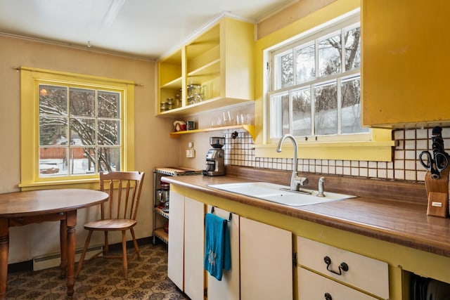 kitchen featuring a baseboard heating unit, decorative backsplash, and a sink