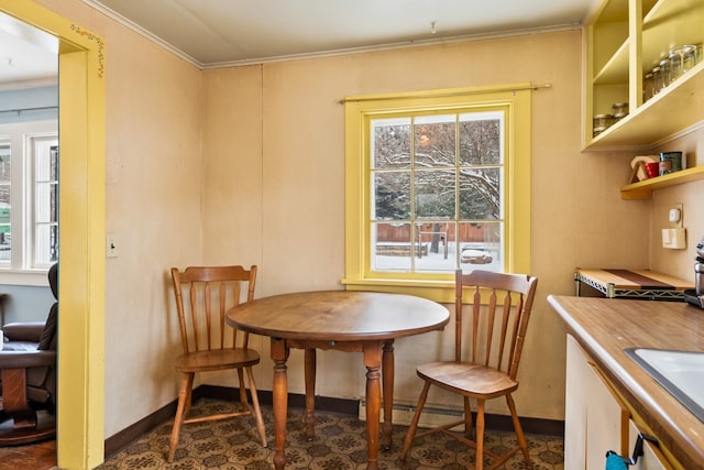 dining space featuring baseboards, a baseboard heating unit, and crown molding