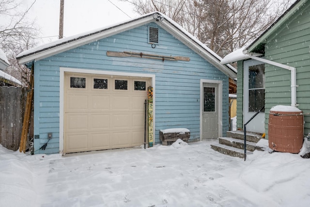 snow covered garage featuring fence