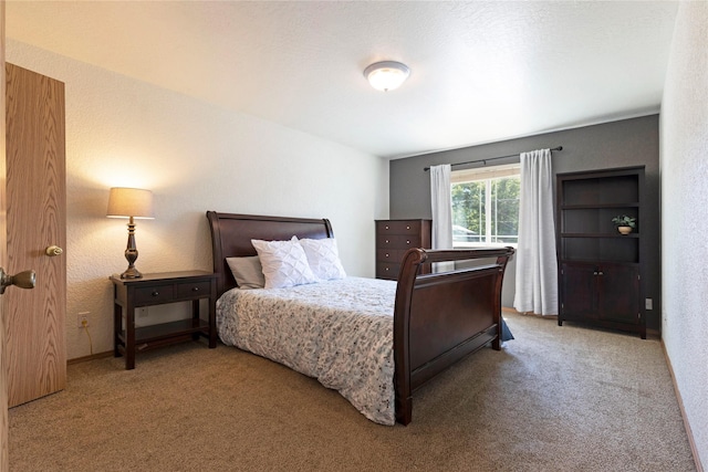 bedroom with carpet floors and a textured wall