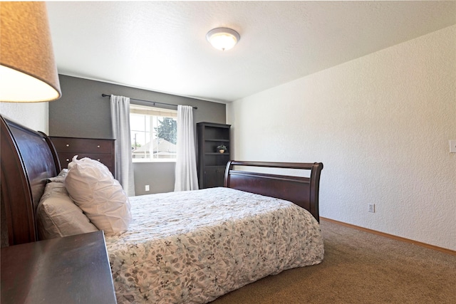 carpeted bedroom featuring baseboards and a textured wall