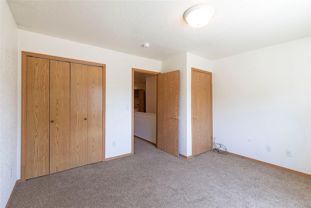 unfurnished bedroom featuring a textured ceiling, baseboards, and carpet flooring