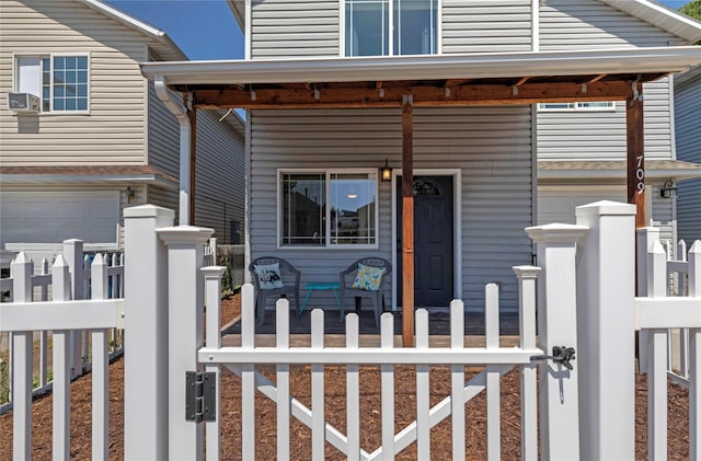 view of front of home featuring a porch, fence, and a gate