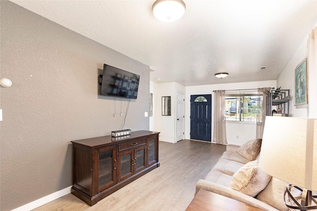 living area with baseboards, wood finished floors, and a textured wall