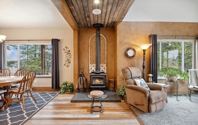 sitting room featuring a healthy amount of sunlight, a wood stove, and wood finished floors