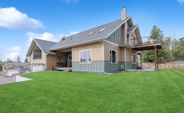 rear view of house with board and batten siding, a chimney, a balcony, and a lawn