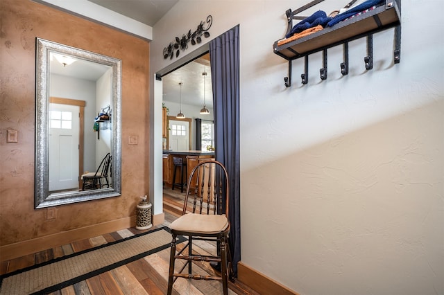 corridor with wood finished floors, plenty of natural light, and baseboards