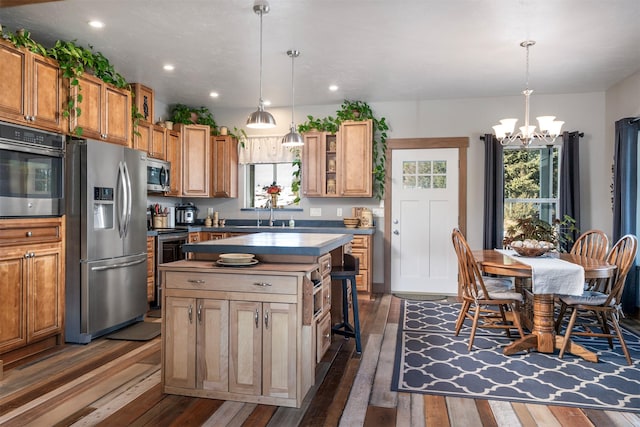 kitchen featuring an inviting chandelier, a center island, dark wood-style floors, and stainless steel appliances