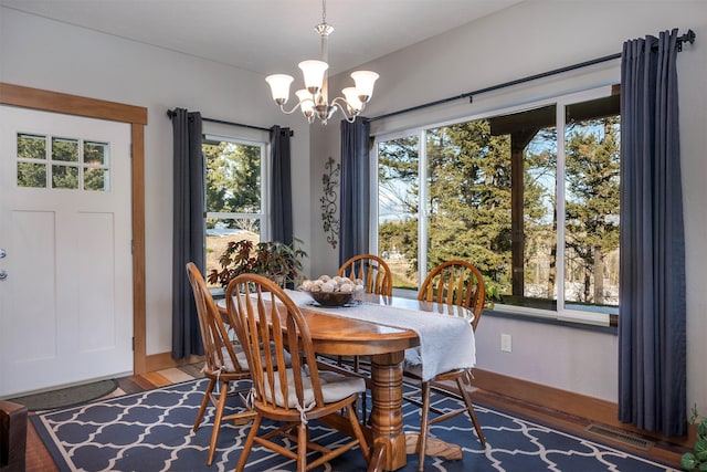 dining space featuring visible vents, an inviting chandelier, and wood finished floors