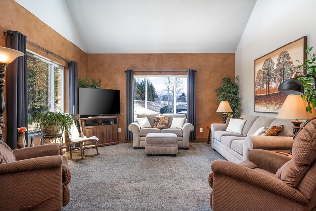 carpeted living area featuring plenty of natural light and high vaulted ceiling