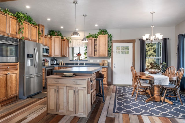 kitchen with stainless steel appliances, dark wood-type flooring, a chandelier, recessed lighting, and a kitchen island