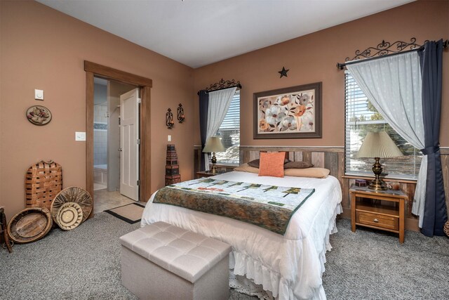 bedroom featuring carpet, wainscoting, and ensuite bath