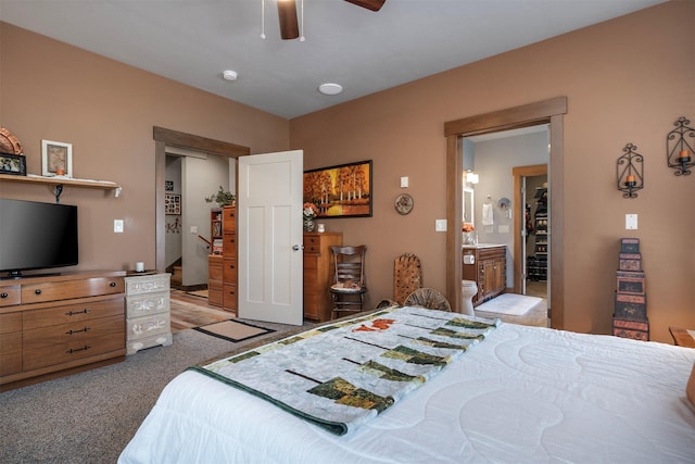 bedroom with light colored carpet, a ceiling fan, and ensuite bath