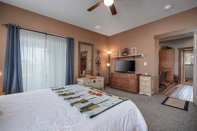 carpeted bedroom with a ceiling fan and a desk