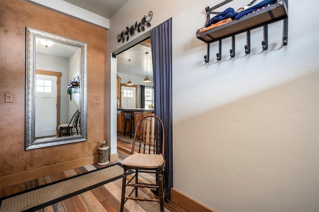 hallway featuring hardwood / wood-style flooring, a textured wall, and baseboards