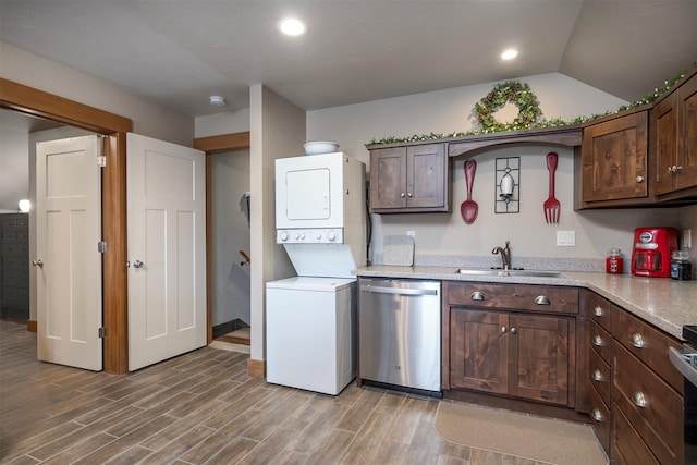 kitchen with a sink, stacked washing maching and dryer, light wood finished floors, dishwasher, and light countertops