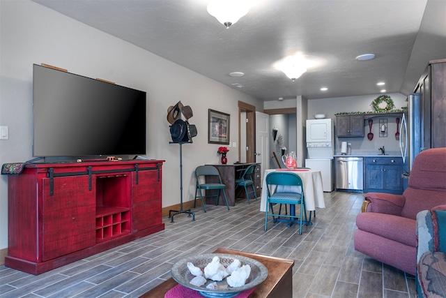 living room with baseboards, stacked washer / drying machine, and wood finish floors