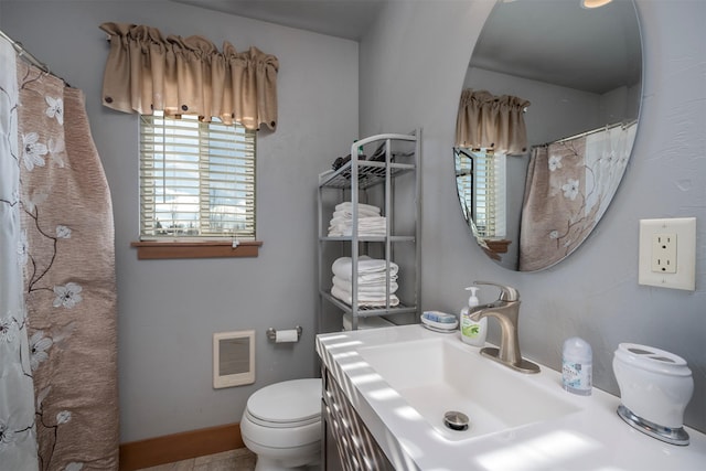 bathroom with toilet, heating unit, and vanity
