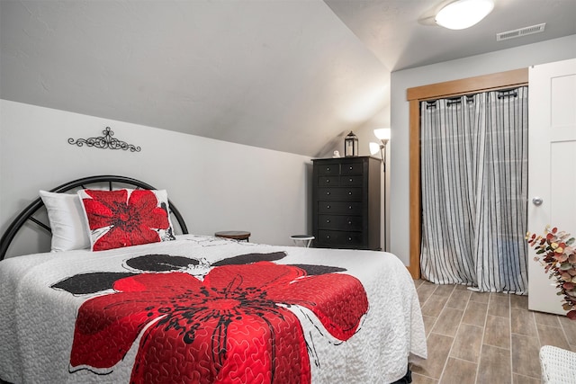 bedroom with wood finish floors, visible vents, and lofted ceiling