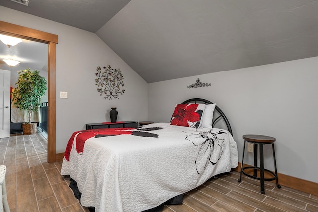 bedroom with visible vents, baseboards, lofted ceiling, and wood finish floors