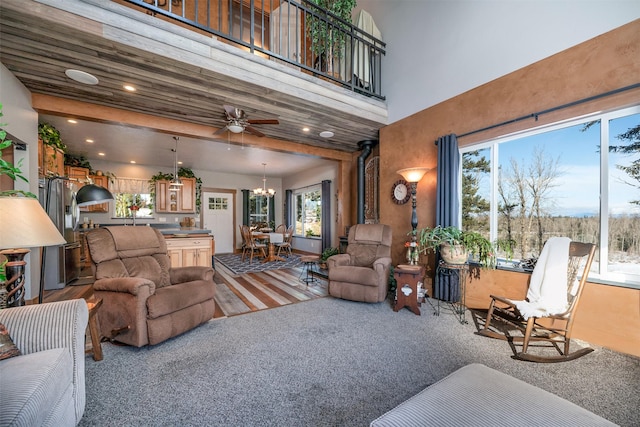 living area with a towering ceiling, carpet flooring, and ceiling fan with notable chandelier