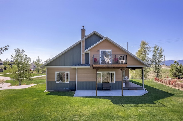 back of property featuring a balcony, a patio, a yard, and a chimney