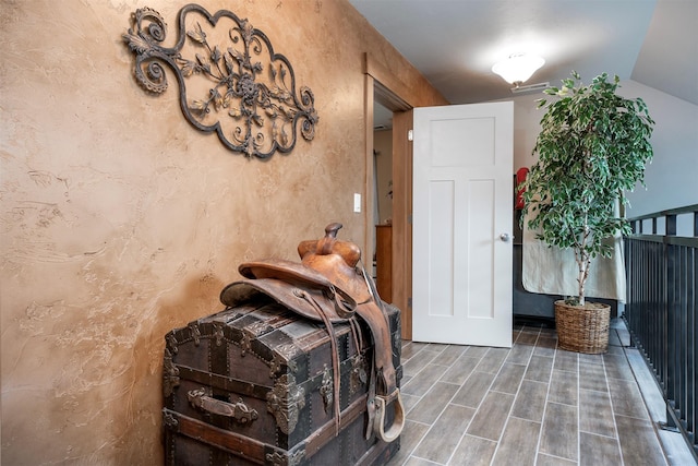 interior space featuring vaulted ceiling, wood tiled floor, and a textured wall