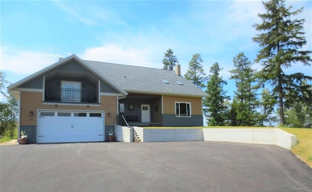 view of front of house with a balcony, a garage, driveway, and a chimney