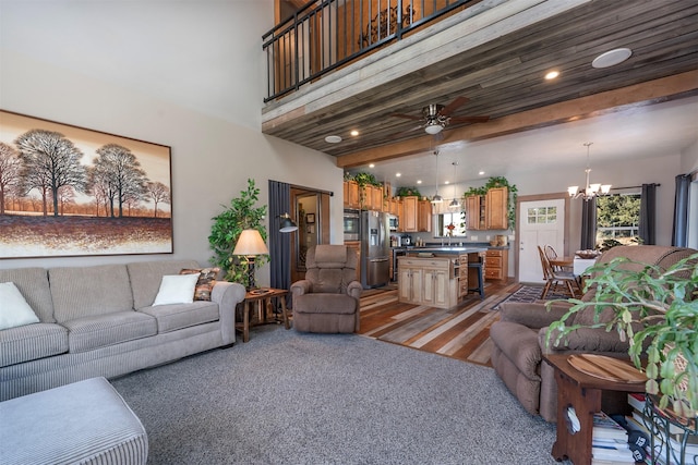 living room with beam ceiling, recessed lighting, ceiling fan with notable chandelier, and a towering ceiling