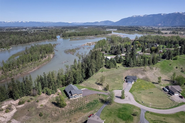 view of property location featuring a water and mountain view and a heavily wooded area