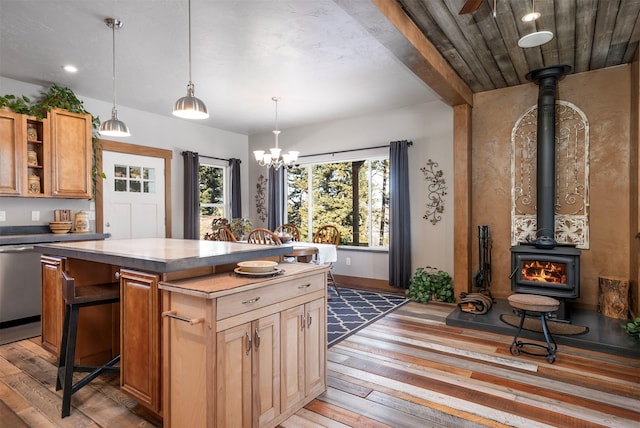 kitchen with plenty of natural light, a kitchen island, a wood stove, and light wood-style floors