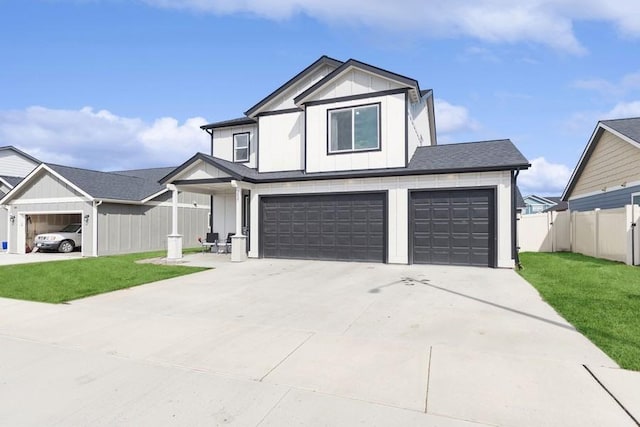 view of front facade with driveway, board and batten siding, a front yard, and fence