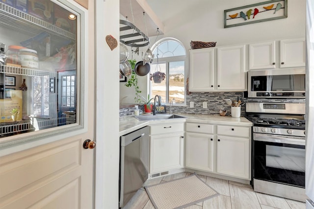 kitchen featuring a sink, white cabinetry, light countertops, appliances with stainless steel finishes, and tasteful backsplash