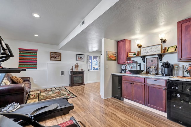 interior space featuring a textured ceiling, light wood-style flooring, recessed lighting, beverage cooler, and visible vents