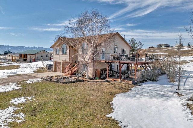 snow covered house featuring a yard, a patio, a deck, a garage, and stairs