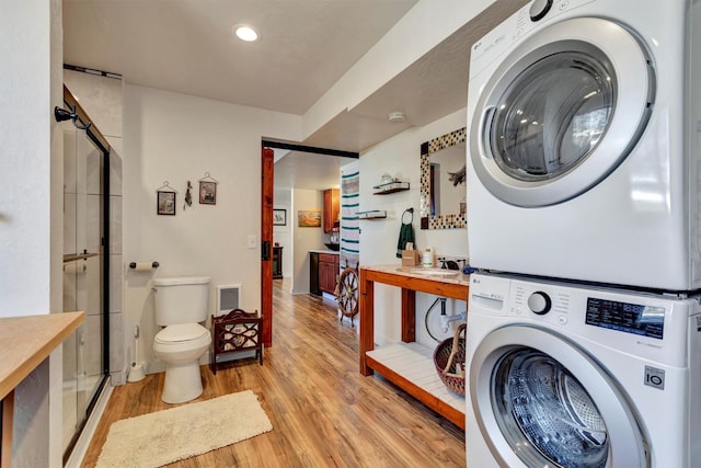 laundry area featuring stacked washer and dryer, laundry area, visible vents, and light wood-style flooring