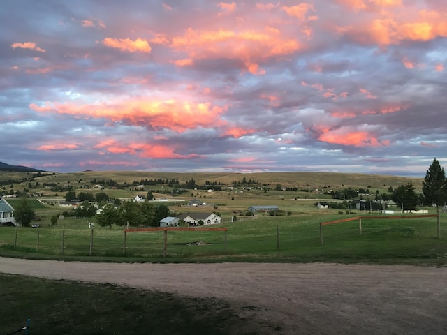 view of property's community featuring a yard, a rural view, and fence