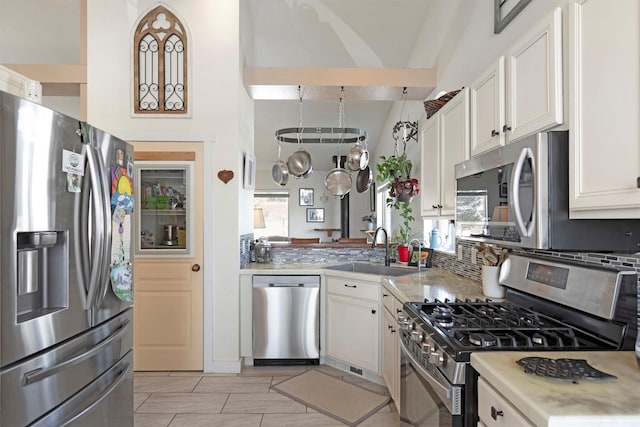 kitchen featuring light countertops, decorative backsplash, appliances with stainless steel finishes, white cabinetry, and a sink