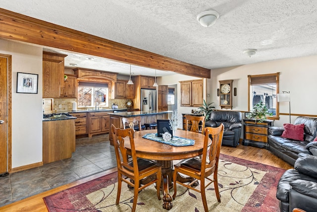 dining area with dark wood-style floors, beamed ceiling, a textured ceiling, and baseboards