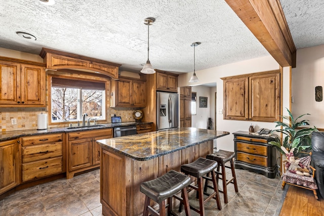 kitchen with a kitchen island, appliances with stainless steel finishes, brown cabinets, and a sink