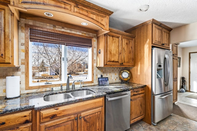 kitchen with appliances with stainless steel finishes, brown cabinetry, a sink, and backsplash