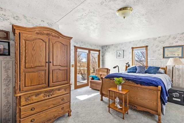 carpeted bedroom featuring wallpapered walls, access to exterior, and a textured ceiling