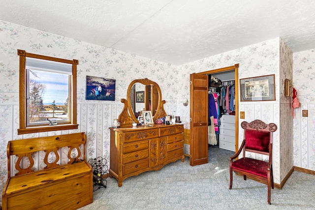 living area with a textured ceiling, carpet floors, baseboards, and wallpapered walls